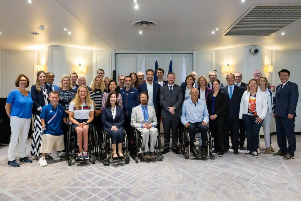 A group of people both standing and in wheelchairs smile together
